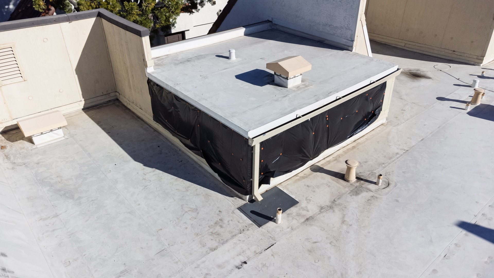 A flat rooftop with a section wrapped in black plastic sheeting for water leak protection